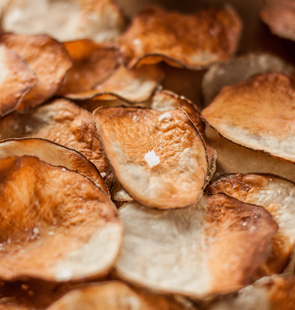Image of a closeup of homemade baked potato chips with a small bowl of dip, healthier than their store-bought counterparts.