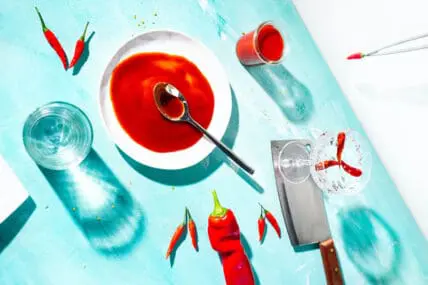hot peppers on table with knife and glass of water for a 5 ingredient hot sauce recipe
