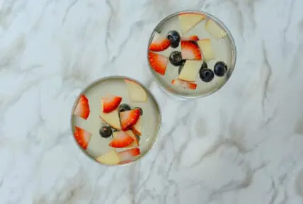 image of a sangria spritzer in cute glasses with floating fruit, strawberries, blueberries and apples.