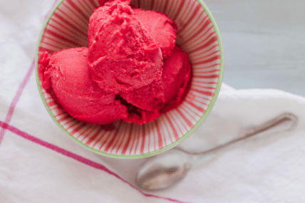 Bright pink sorbet in a striped bowl, make this easy sorbet recipe via Organic Authority