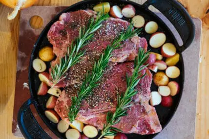 porterhouse steaks on grill pan with potatoes and rosemary