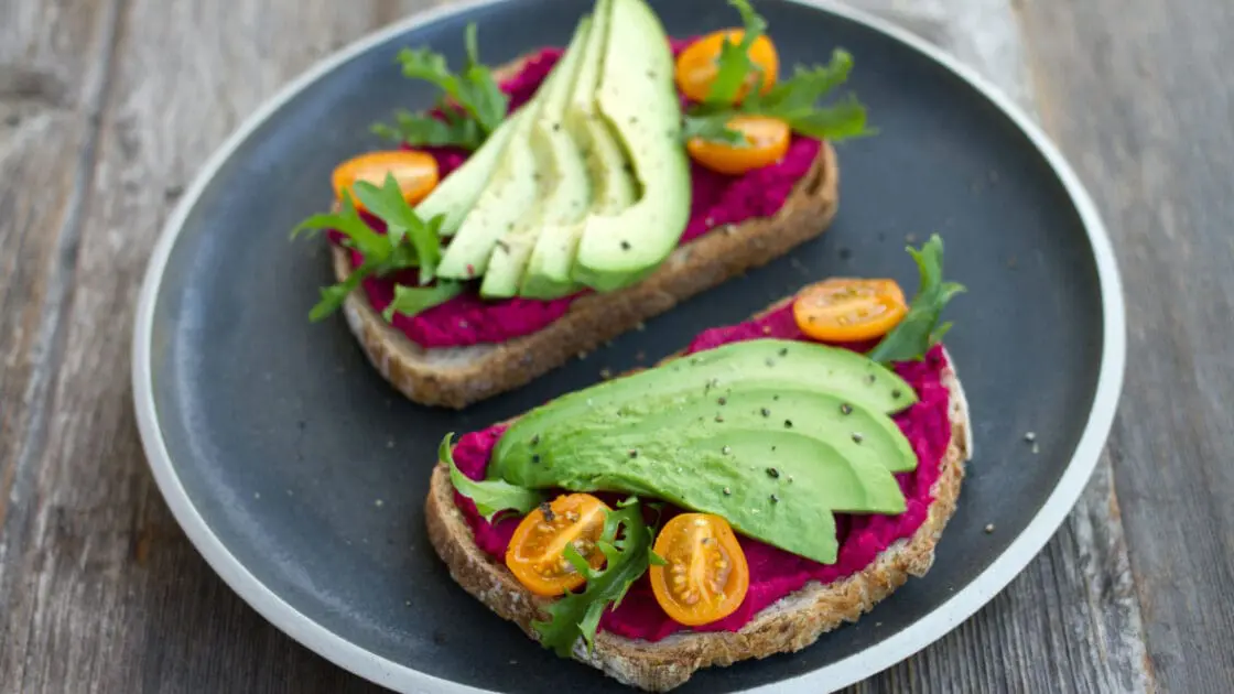 Avocado and beet humus on toast with cherry tomatoes and arugula