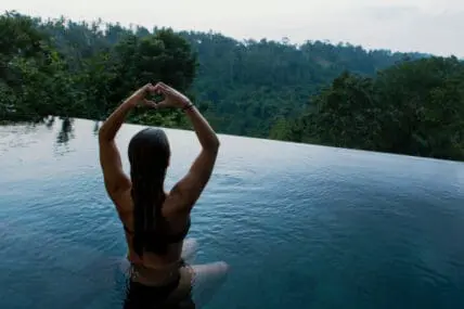Kirtan quiets the mind and opens the heart. Image of Woman sitting in infinity pool looking over Ubud.