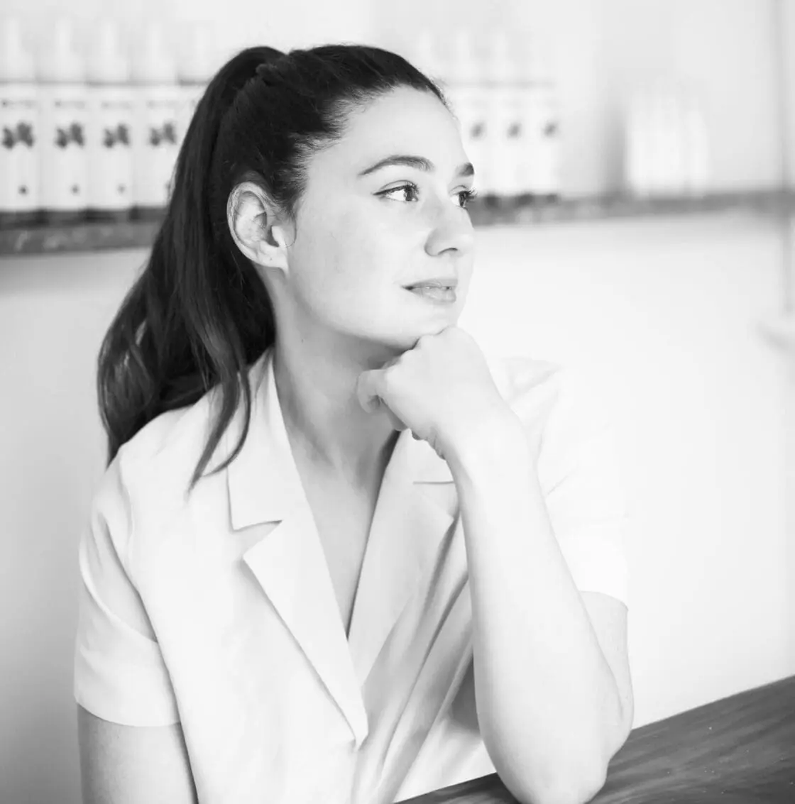 Black-and-white portrait of a woman with a ponytail resting her chin on her hand