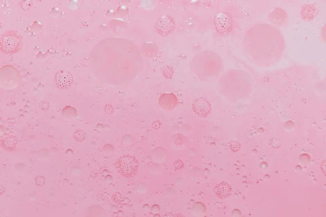 Image of light pink oily liquid up close to surface showing bubbles for clean face serums made of natural ingredients.