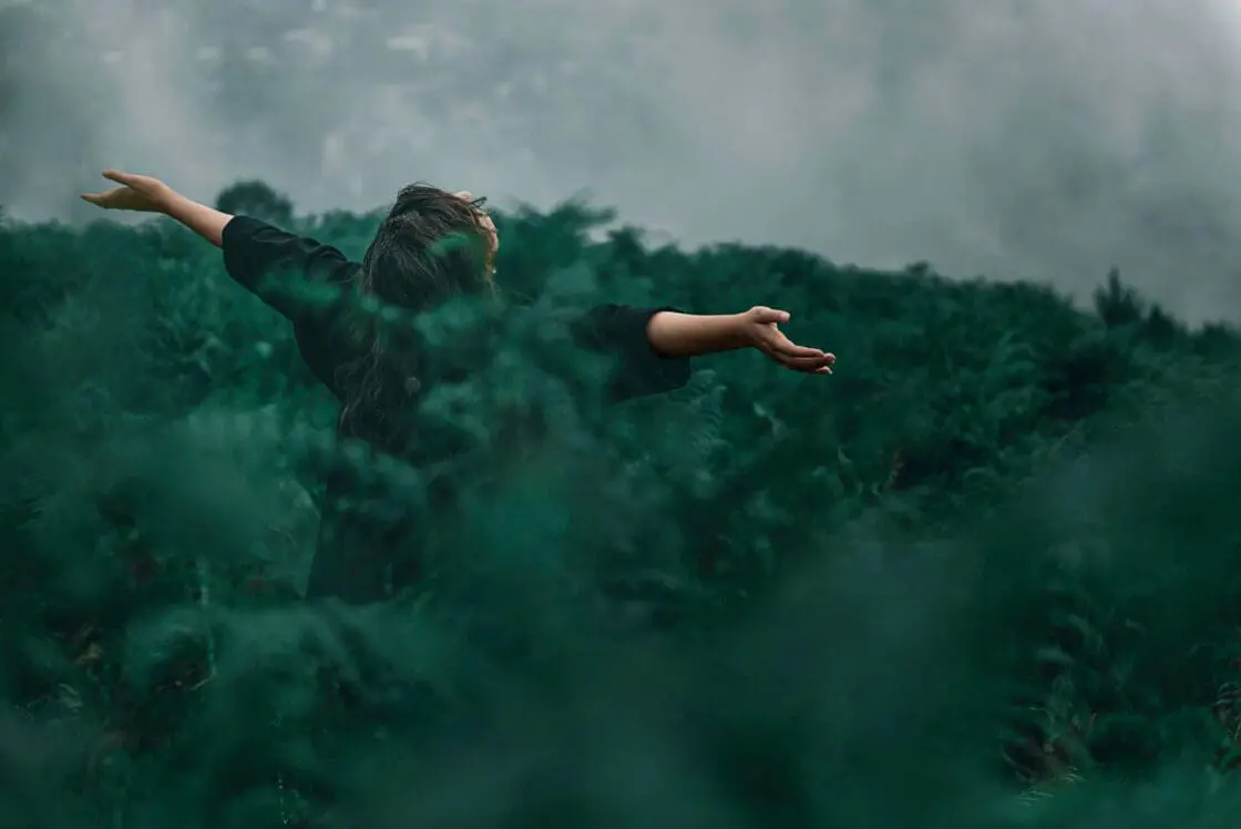Quantum energy healing as shown by woman in forest, arms outstretched via Organic Authority