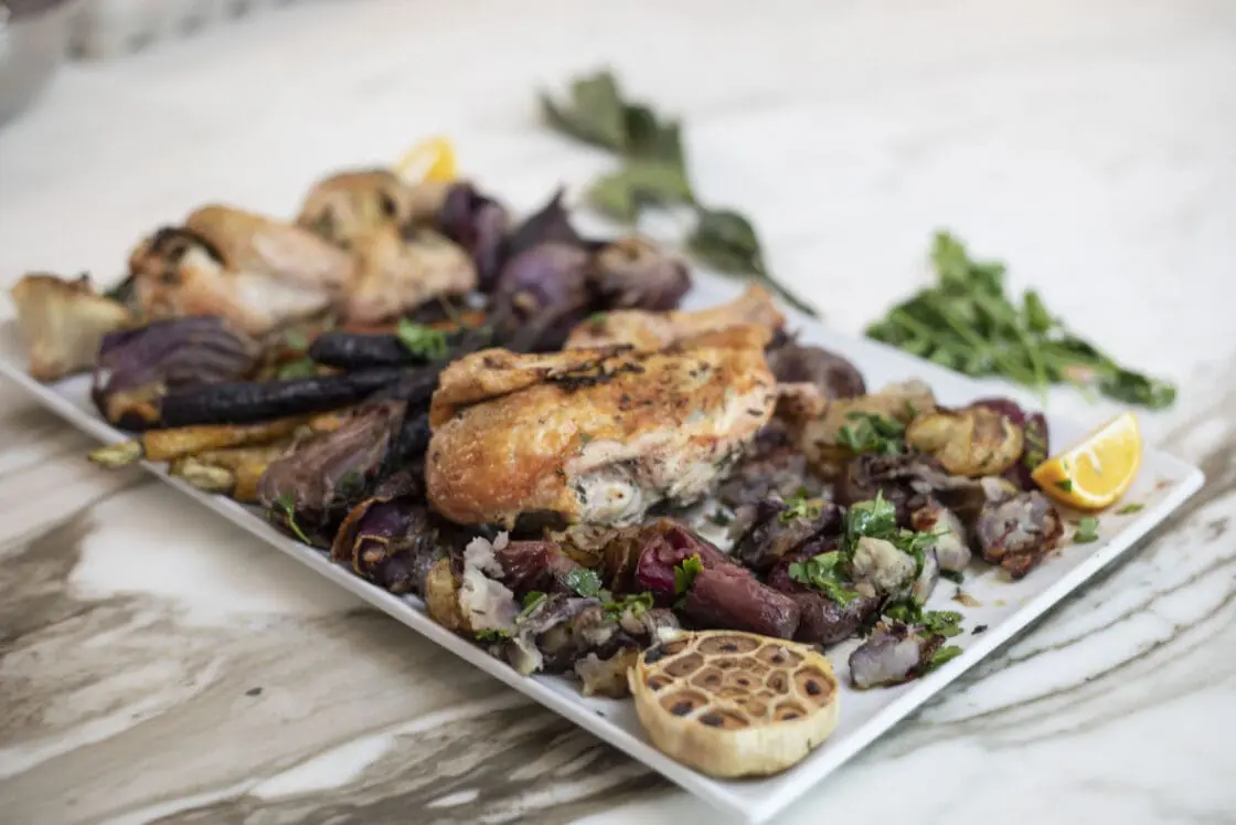 roasted sheet pan chicken with rainbow carrots and potatoes on a platter.