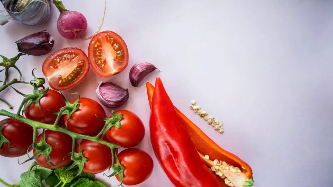 red pepper, tomato and garlic and radish on a white background are all foods that support building vegan collagen