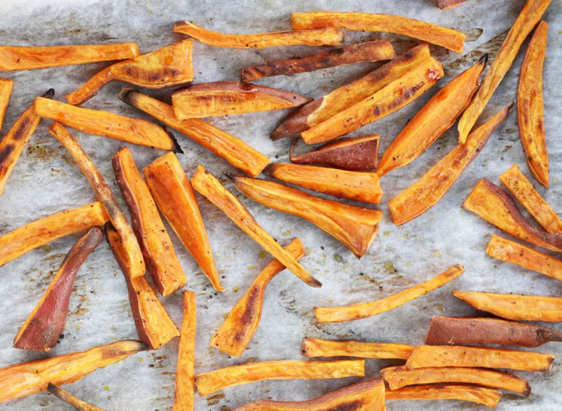 Image of a handful of crispy sweet potato fries on parchment paper.