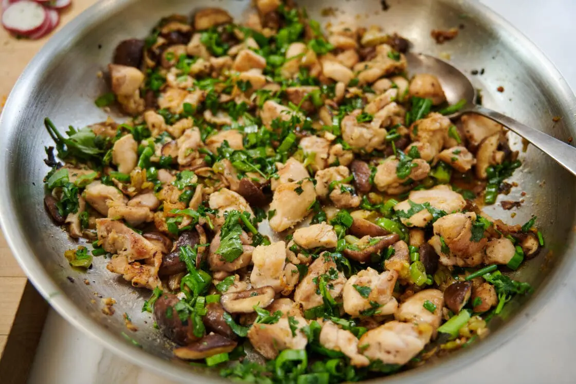 Image of sauteed chicken and shiitake mushrooms in a stainless steel pan.