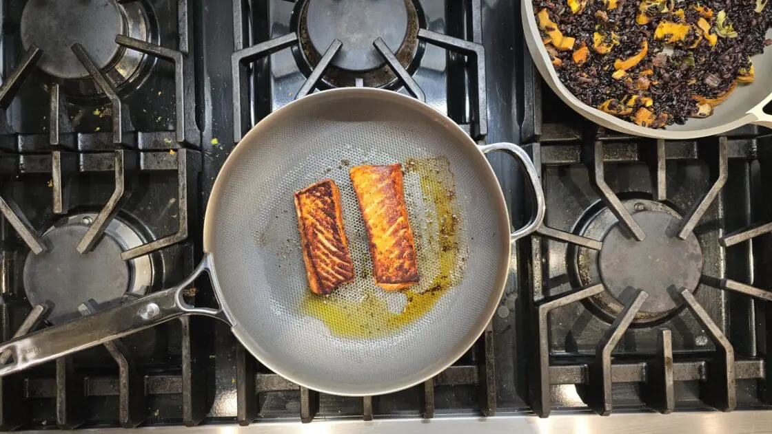 Image of an overhead view of a stove with salmon cooking in an Always Pan by Our Place