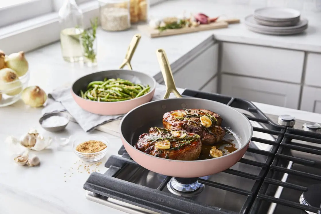 Image of the GreenPan GP5 ceramic cookware set in cloud cream, with two pans full of food on a stovetop.