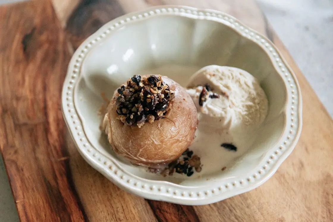 Image of plated slow cooker baked cinnamon apples served with a scoop of vanilla ice cream which pairs well with spiced apples