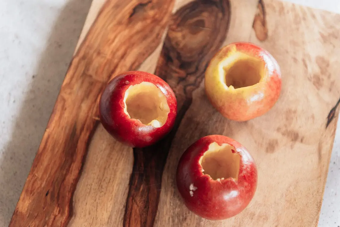 image of 3 fresh apples cored on a natural wood cutting board for slow cooker desserts