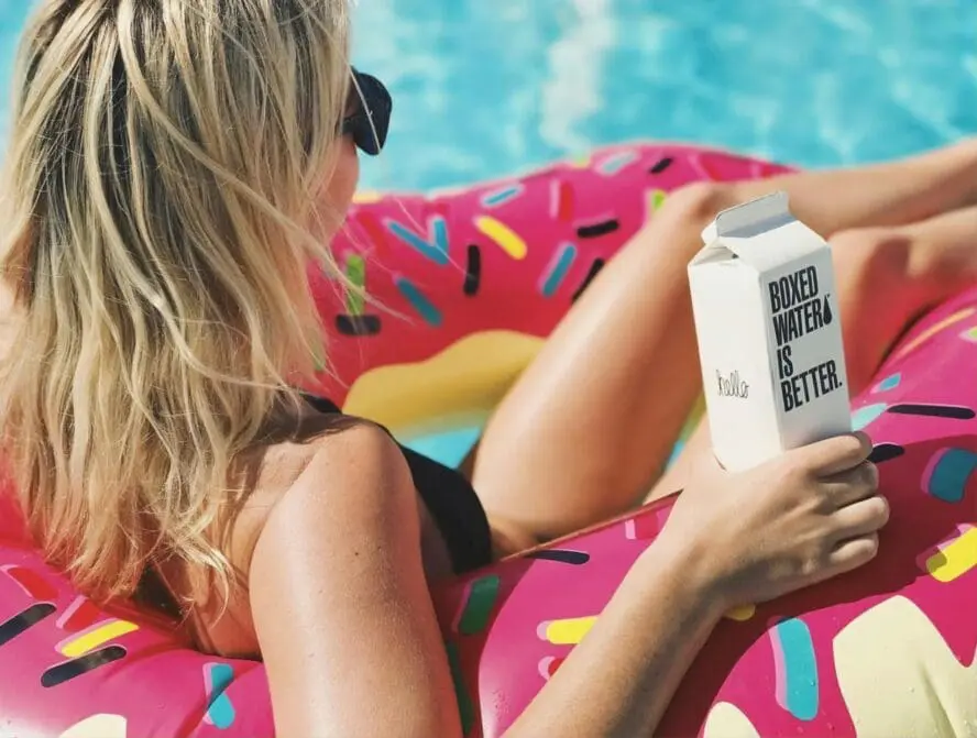 Image of woman floating in floaty in water, summer skin care.