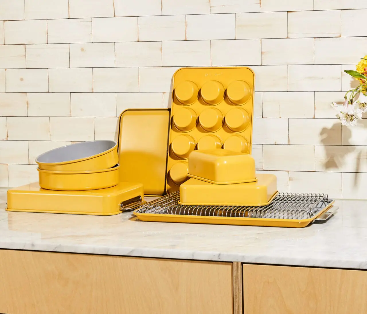 Image of the Caraway 11-piece bakeware set in a cheery yellow color (marigold), with the loaf pan prominently displayed.