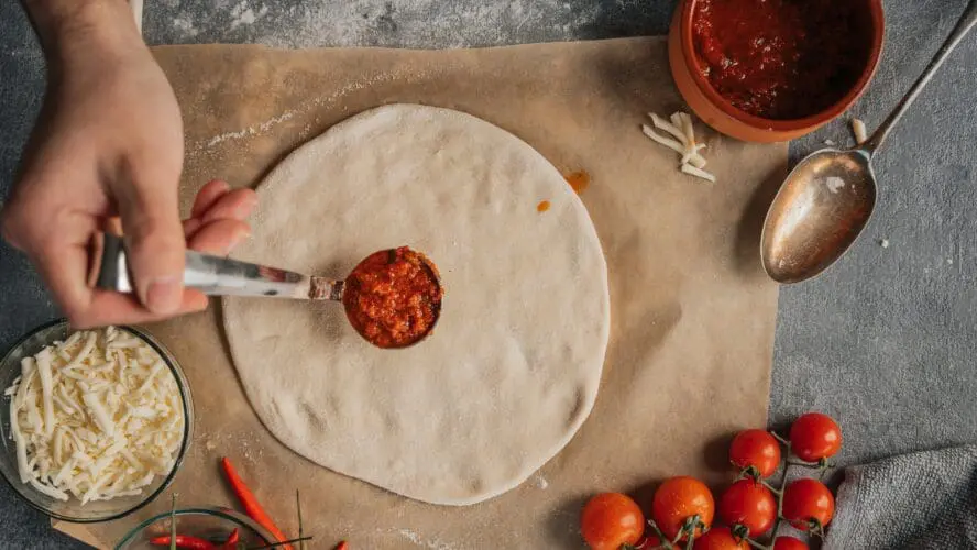 image of organic pizza dough with a dollop of marinara sauce