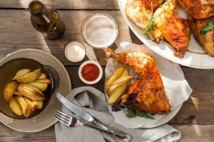 Overhead image of a Labor Day outdoor spread including grilled chicken under a brick, beer, ketchup, and mayo in ramekins