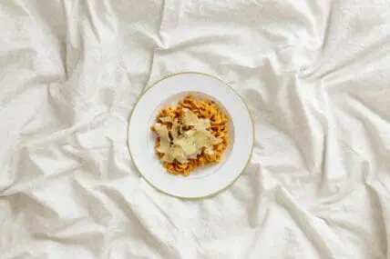 image of a bowl of pasta on a bed. Registered Dietitians suggest that what you eat before you go to bed, may affect your mood. what what you eat for midnight snacks