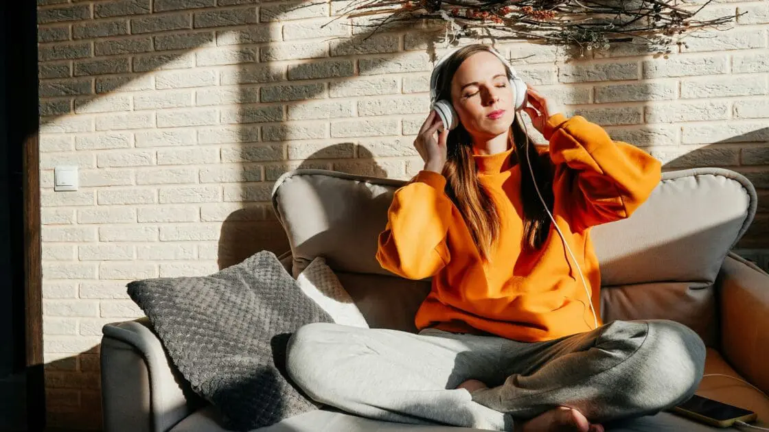 Woman listening to music on headphones while sitting on a couch