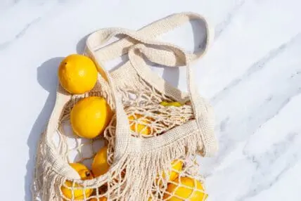 image of a bag of lemons in a reusable produce bag begging the question, is taking vitamin c worth it?