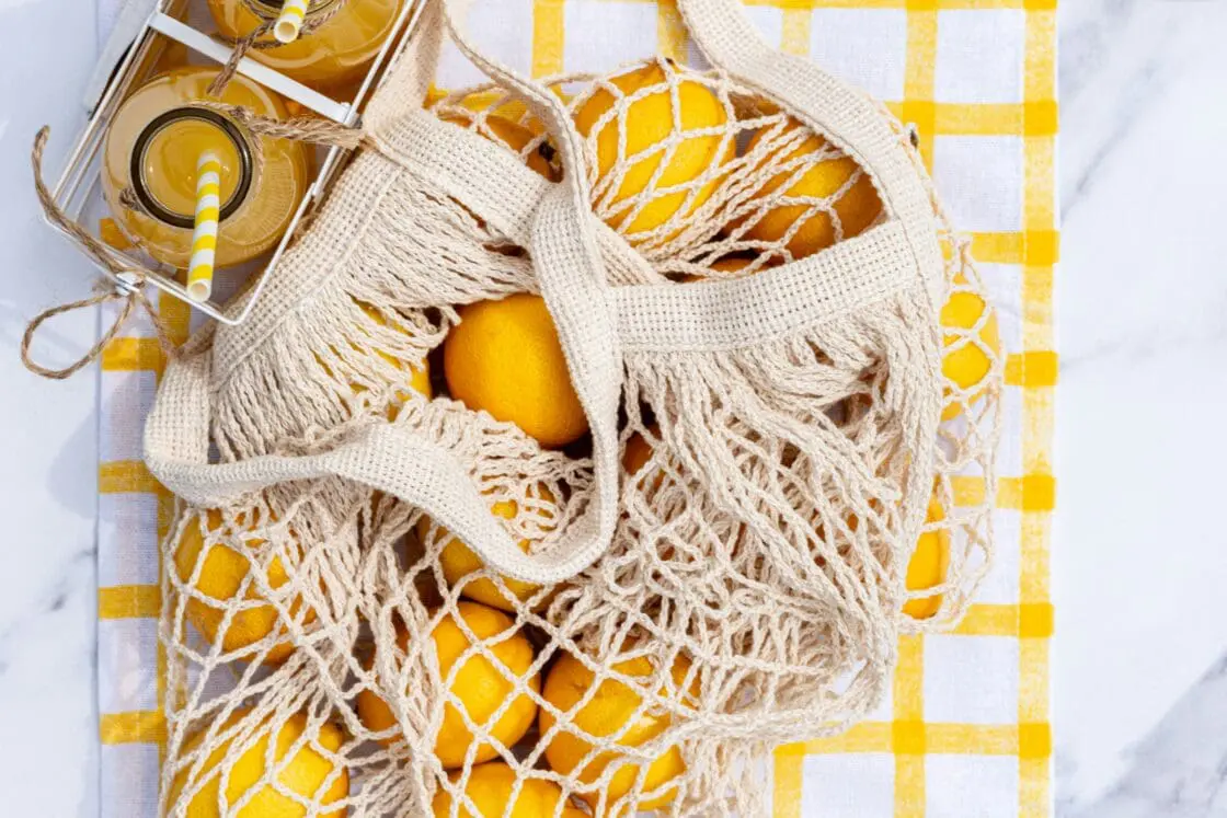 image of a bag of lemons and a jar on lemonade from an overhead view. But is taking vitamin c for the flu or cold worth it? 