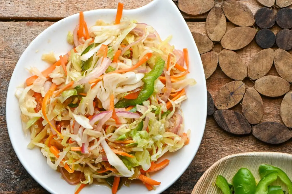 Image of sauteed cabbage on a plate with other sauteed veggies.