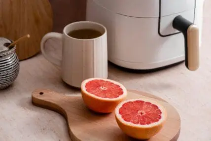 image of a halved grapefruit on a cutting board with a cup of black coffee