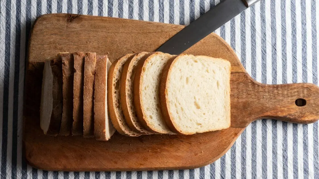 Image of a loaf of white bread sliced on a cutting board