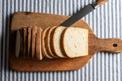 Image of a loaf of white bread sliced on a cutting board