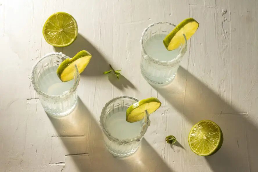 three salted glasses full of mezcal with lime slices
