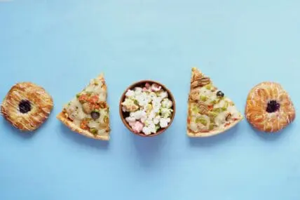 image of junk food like pizza, doughnuts, and candy from overhead on a blue background