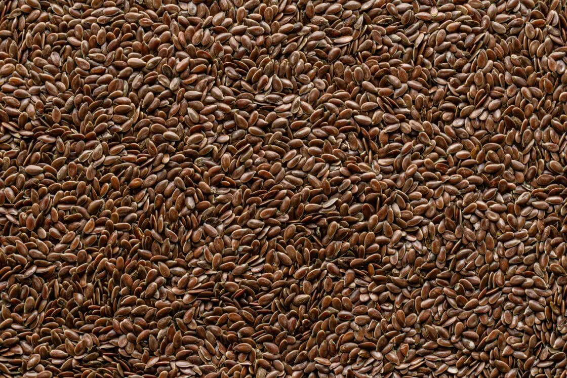 Close-up image of a pile of brown flax seeds, which are cold-pressed into flaxseed oil.