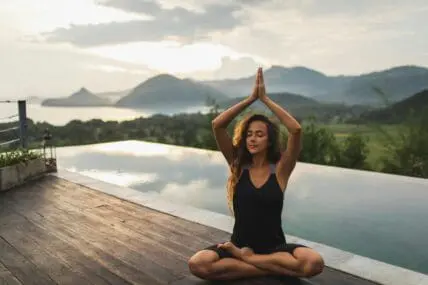 woman doing yoga by a pool overlooking mountain scenery showing how to avoid common yoga injuries