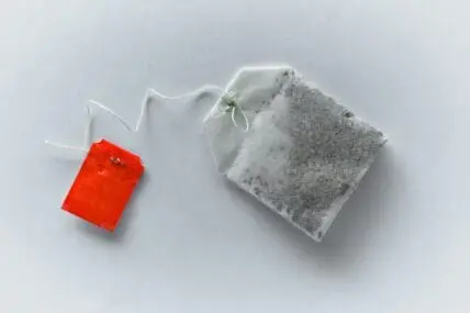 Image of a single tea bag on a white background, with a red tag. Research has shown a tea bag's microplastic content is through the roof.