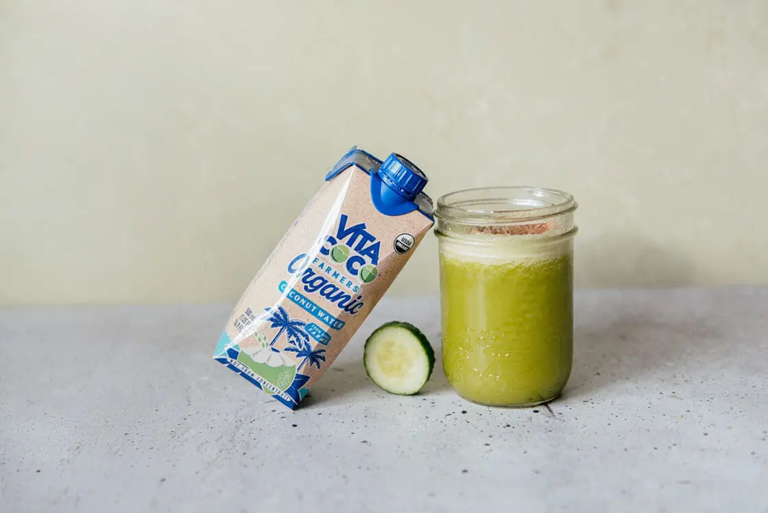 Image of a coconut water pineapple juice cocktail in a glass jar, with a carton of Vita Coco Farmer's Organic coconut water leaning against it. 