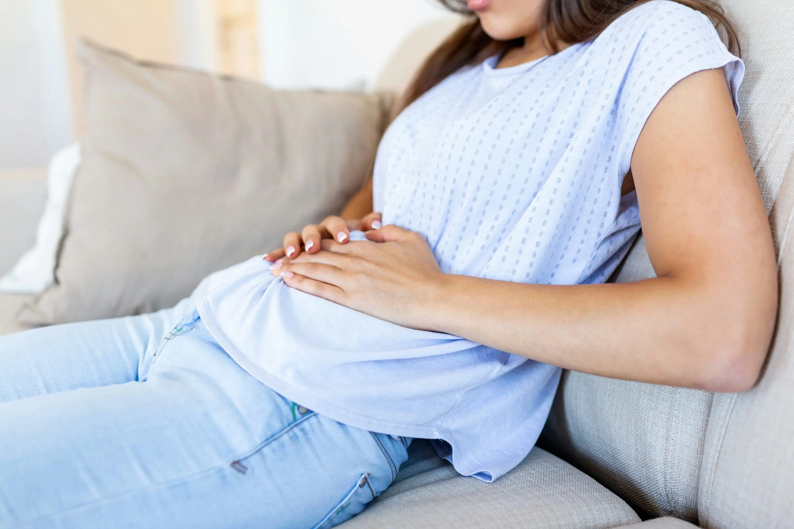 Image of woman holding stomach seeking natural heartburn relief