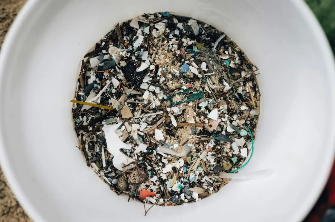 Image of a large plastic bucket filled with tiny bits of plastic debris of varying sizes and colors. How much microplastic do we consume?