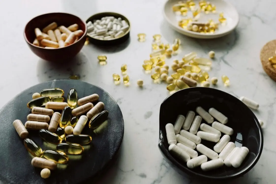 Image of various bowls on a marble countertop, filled with different supplements and pills.