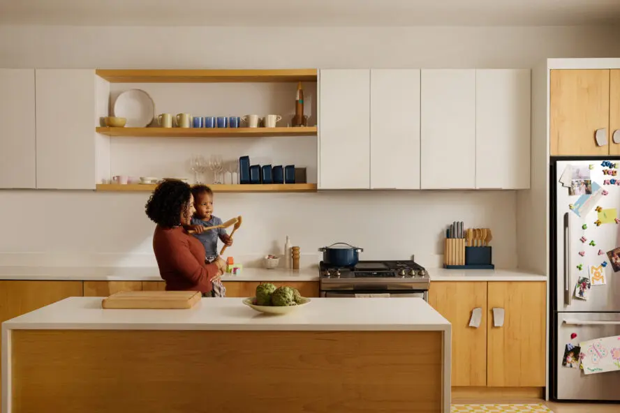 Caraway Mother's Day Campaign Image of mother standing with child at kitchen island with butcher block