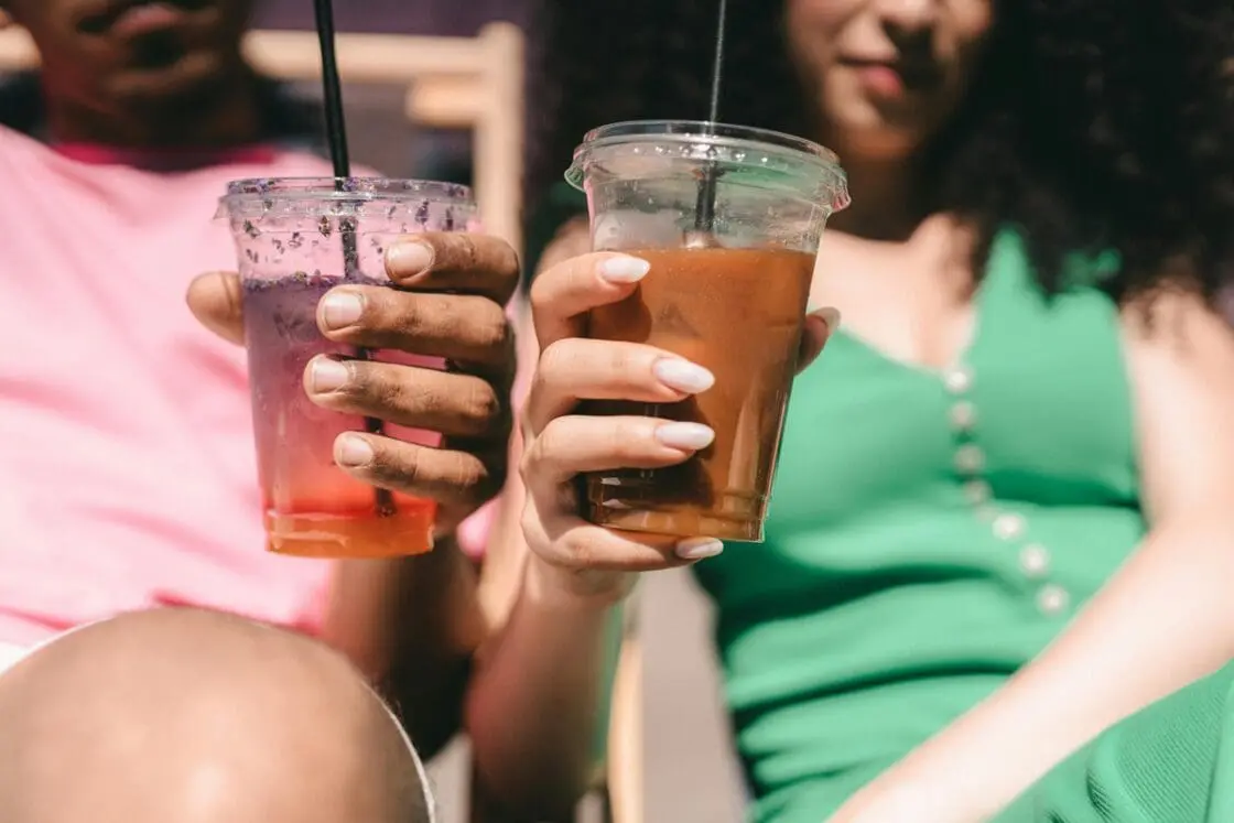 Image of two people holding plastic cups with iced coffee drinks.