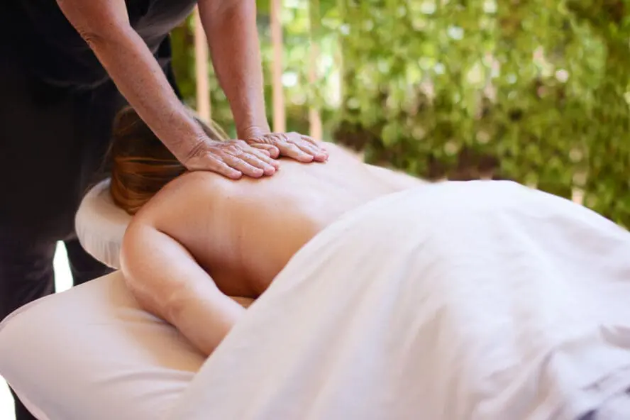 An image of a woman draped in a towel, lying on a table and receiving a back massage at Cal-a-Vie Health Spa.