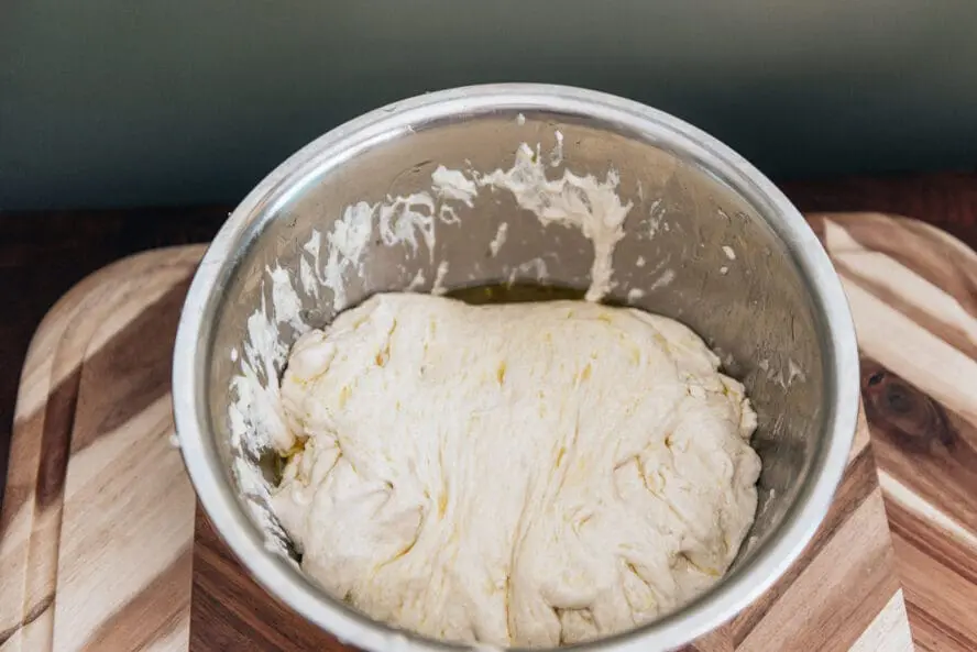 Image of focaccia bread dough in an oiled bowl left to rise.