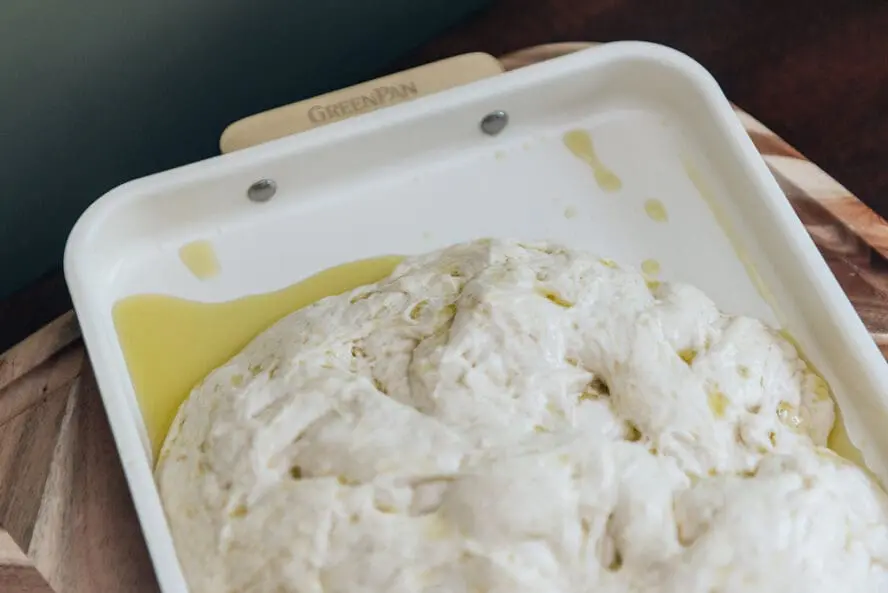 Image of focaccia dough in an oiled pan to prepare for baking.