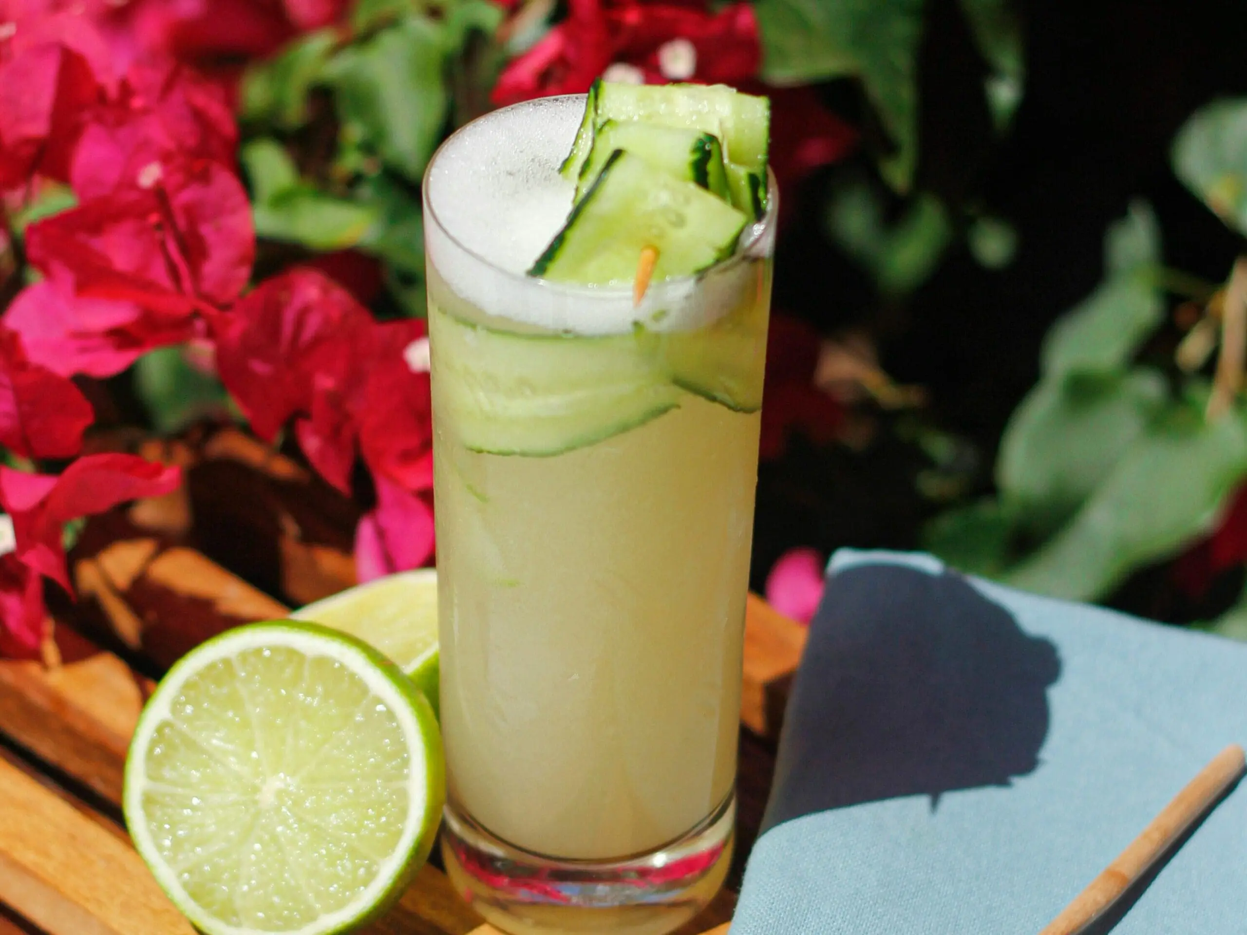 Image of a green juice drink garnished with a ribboned cucumber and lime.