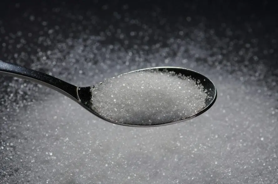 Image of a spoon overflowing with stevia on a black background.