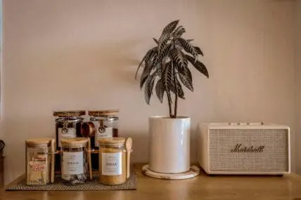 Image of a kitchen counter with little glass jars of sugar, stevia, coffee, and creamer.
