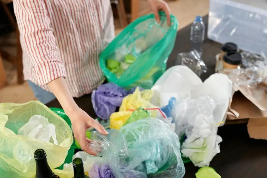 Image of a woman sorting through a pile of plastic bags of various colors.