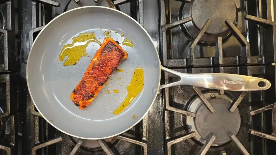 Image of a GreenPan Valencia Pro fry pan on a stovetop cooking a salmon fillet.