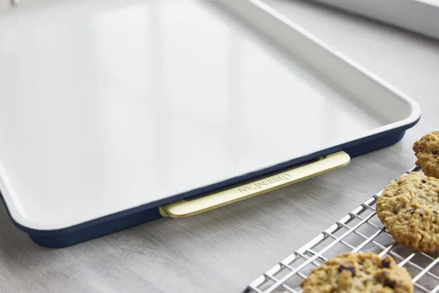 Image of the GreenPan Reserve half sheet pan with the iconic gold handles, next to the cooling rack with cookies.